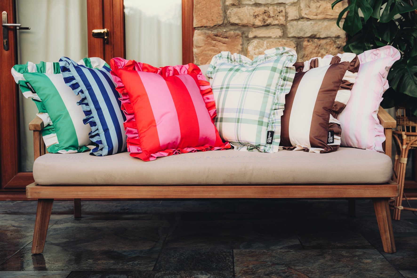 Bright colourful array of outdoor cushions in various patterns overflowing from a pink bathtub.